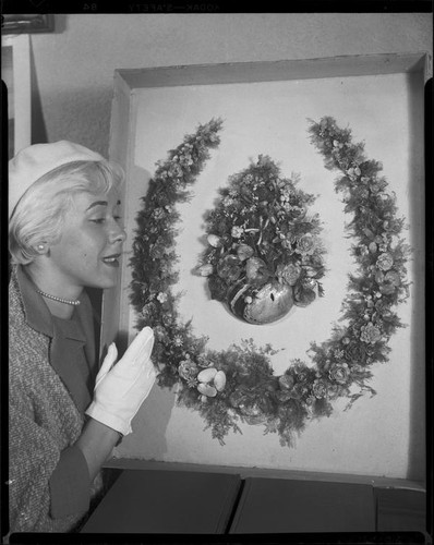 Dane Gorrell with 1888 horseshoe-shaped shell art wreath made by poet Ina Donna Coolbrith, Santa Monica, 1953