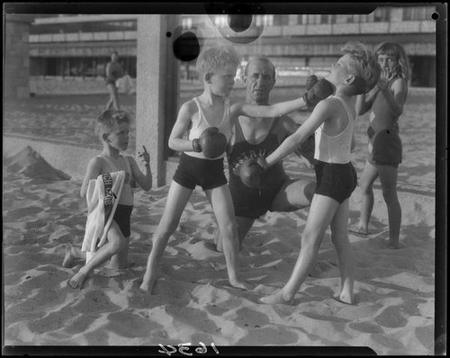 Identical triplet sons of politician George W. Neal playing on the beach with other children, Santa Monica, circa 1930's