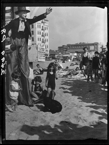 Clown on stilts with children on beach, Santa Monica, 1928