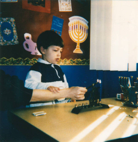 Child lights Menorah during Hanukkah