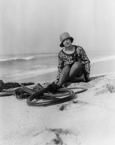 Woman sitting next to algae at the beach