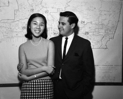 Unidentified man and woman pose in front of Los Angeles County map