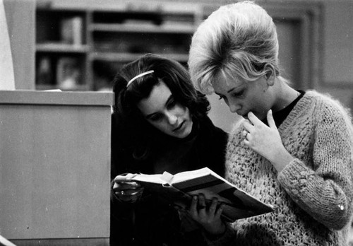 Two young women sharing a book