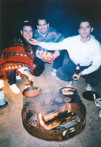 Friends at a campsite cooking hot dogs