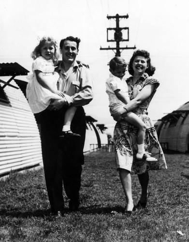 Young family pose outside their quonset unit