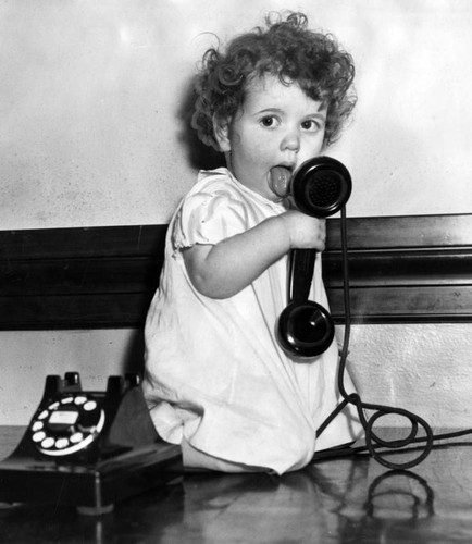 Little girl plays with a telephone