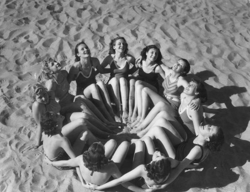 Young women form a circle on the sand