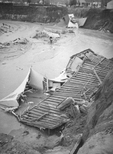 L.A. River flooding, water swirling around crushed houses in North Hollywood