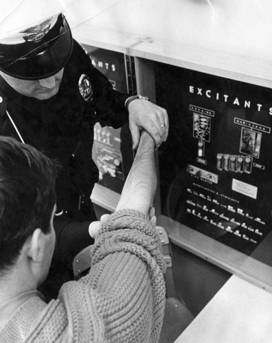 Police officer checks narcotics suspect's arm