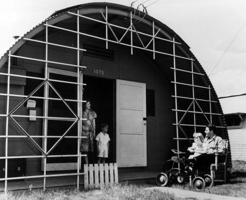A young family outside their quonset unit