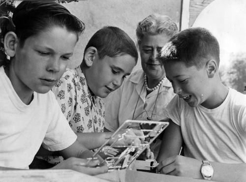 Teenagers help younger boys build model cars