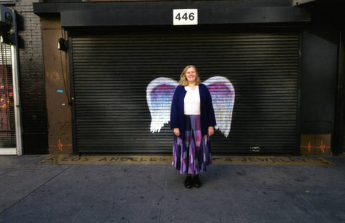 Unidentified woman posing in front of a mural depicting angel wings