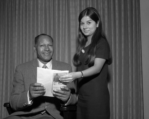 Councilman Tom Bradley holding a campus guide brochure