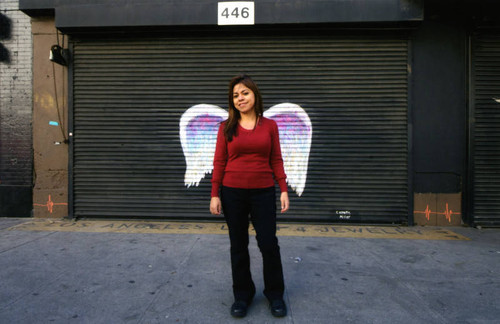 Unidentified woman posing in front of a mural depicting angel wings