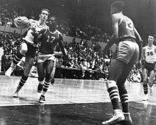 Packing ball, Tom Levin (52), drives for layup against helpless Jan Taylor (17)