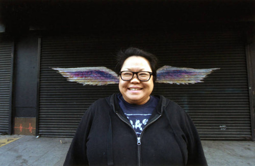 Celia Esguerra smiling and posing in front of a mural depicting angel wings