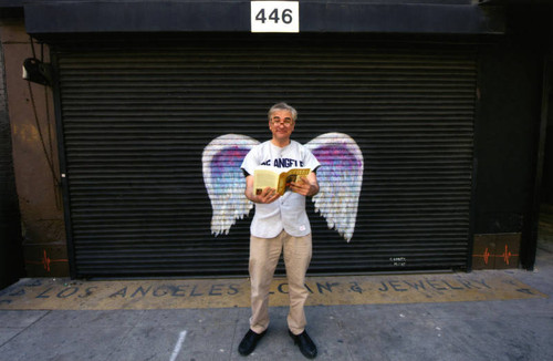 David Kipen posing in front of a mural depicting angel wings