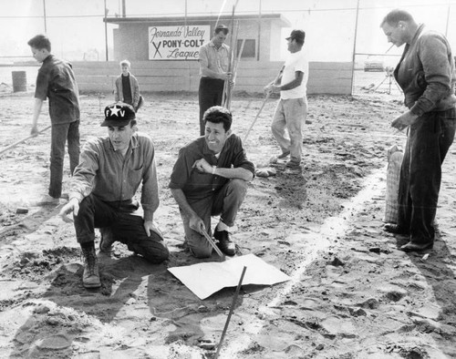 Pony-Colt League president Ray Rasori, kneeling left, supervises work on field