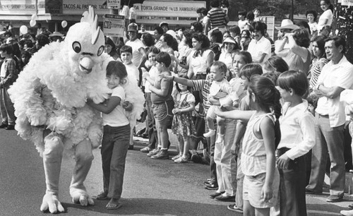 Dancing chicken in parade hugs child