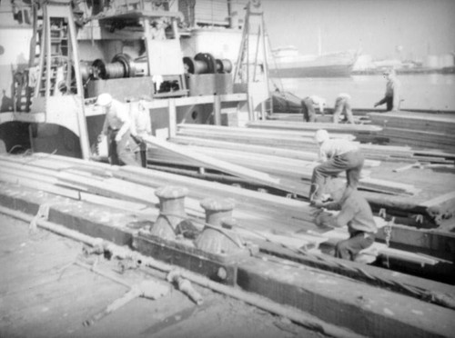 Stacking lumber on a ship at the harbor