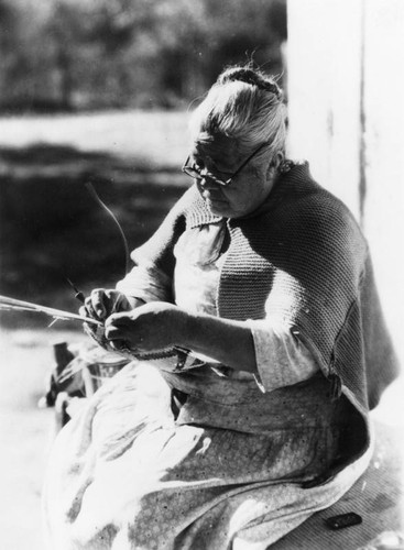 American Indian woman weaving basket