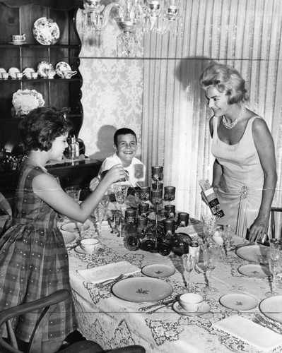 Carol, 11, and Terry, 9, help mommy light candles for dinner party