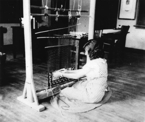 American Indian girl weaving on loom