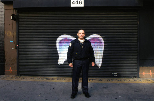 Unidentified security guard posing in front of a mural depicting angel ...