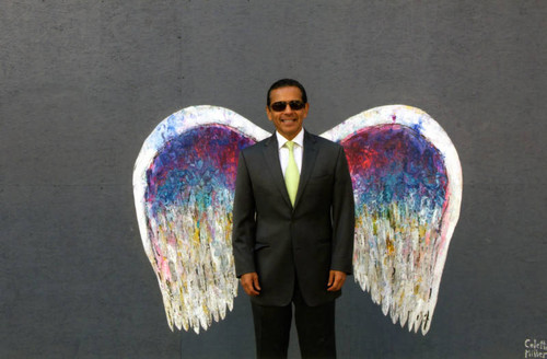 Antonio Villaraigosa posing in front of a mural depicting angel wings