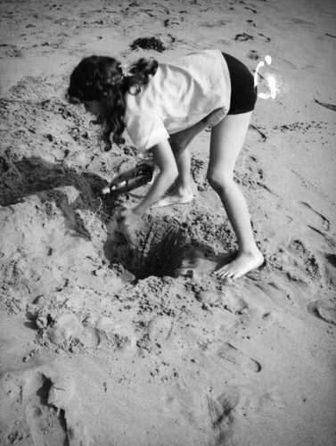 Girl digging a hole in the sand at the beach