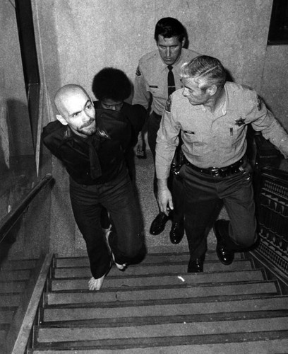 Charles Manson with deputies on stairs