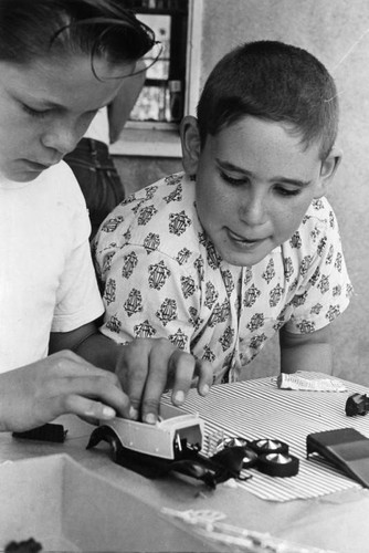 Teenagers help younger boys build model cars