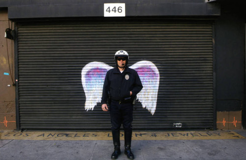 Unidentified traffic officer posing in front of a mural depicting angel wings