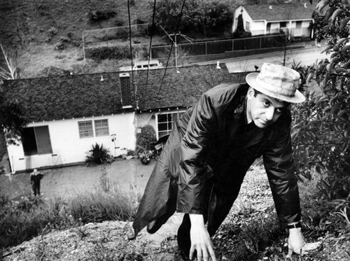 Larry Dorn climbs hill where crack threatens his home, in background, and 11 others