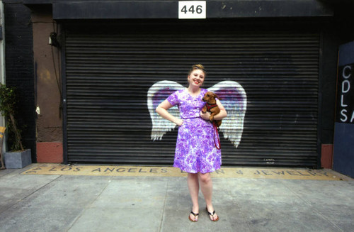 Katie Dunham posing in front of a mural depicting angel wings