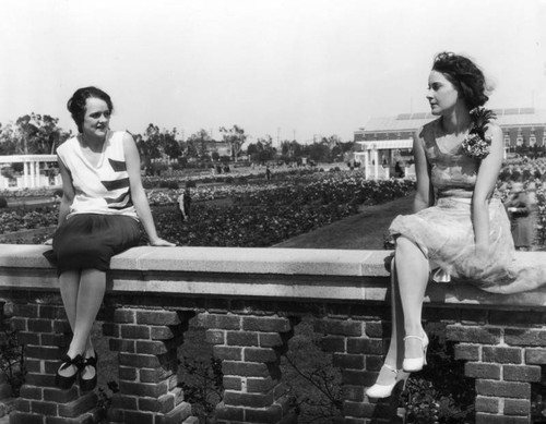 Two women sitting on wall