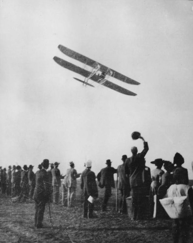 Biplane over waving crowd