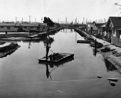 Debris, garbage scow and oil derricks blight the view