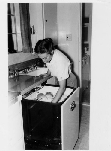 Woman loading dishwasher in suburban kitchen