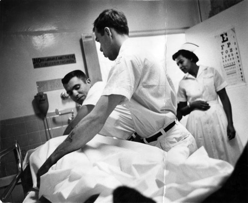 Nurse Ruth Davis watches attendants bring in patient