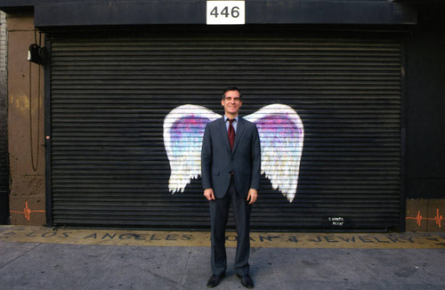 Mayor Eric Garcetti posing in front of a mural depicting angel wings