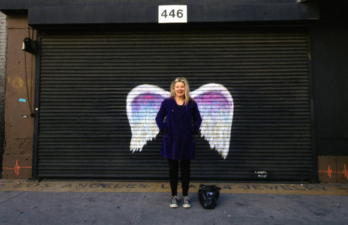 Unidentified woman posing in front of a mural depicting angel wings