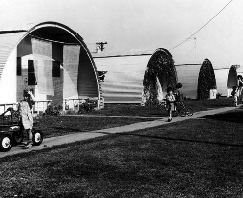 Children play outside their quonset homes