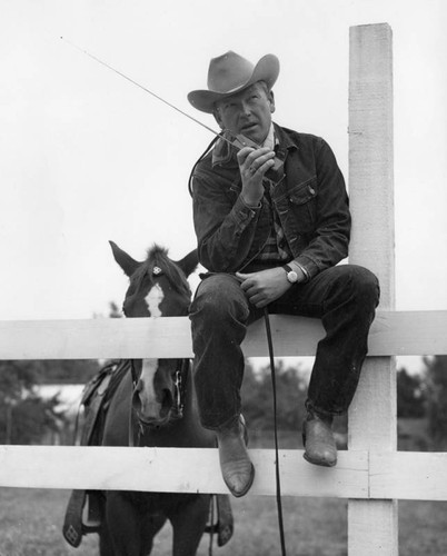 Rex Allen on ranch fence