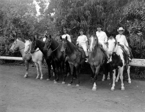 Unidentified young girls ride horseback