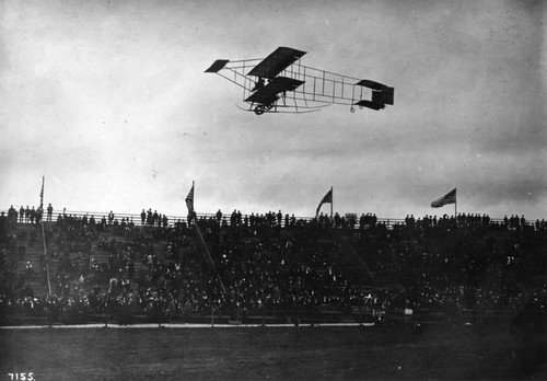 Spectators watch a biplane in flight