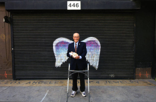 Unidentified man in a suit posing in front of a mural depicting angel wings