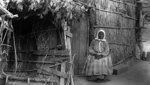 Native American sits by her door