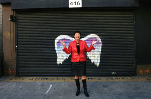 Carol Schatz posing in front of a mural depicting angel wings