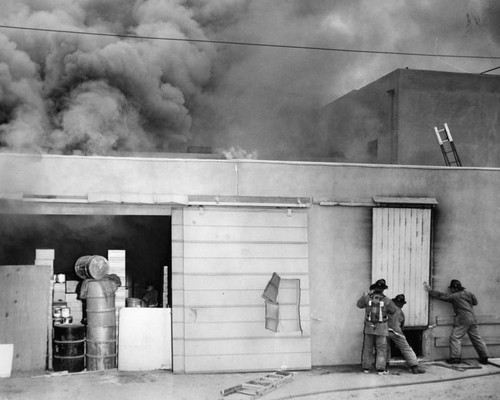 Store roof ablaze as firemen arrive